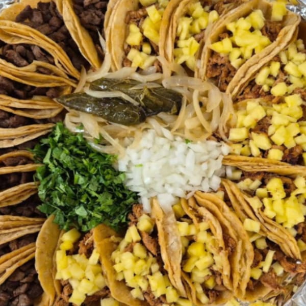 A platter of LA Taco Cantina's Mexican tacos with various fillings, onions, cilantro, and jalapeños.