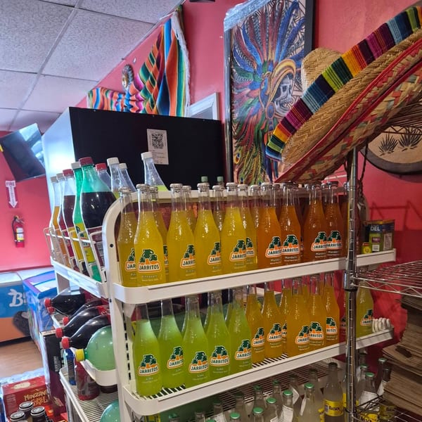 Shelves filled with various Jarritos soda flavors, including pineapple, mandarin, lime, and passion fruit.
