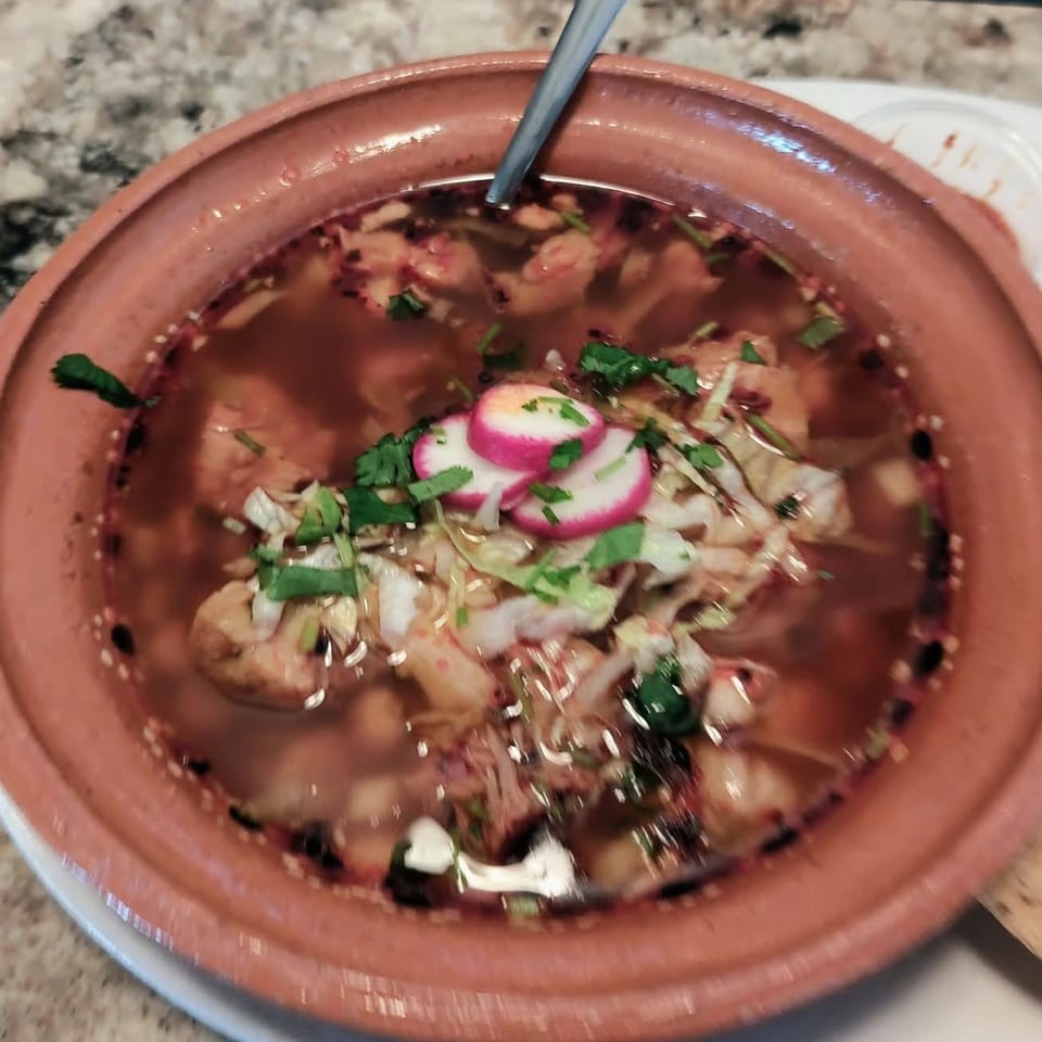A close-up of a bowl of LA Taco Cantina's pozole, garnished with radishes and cilantro.